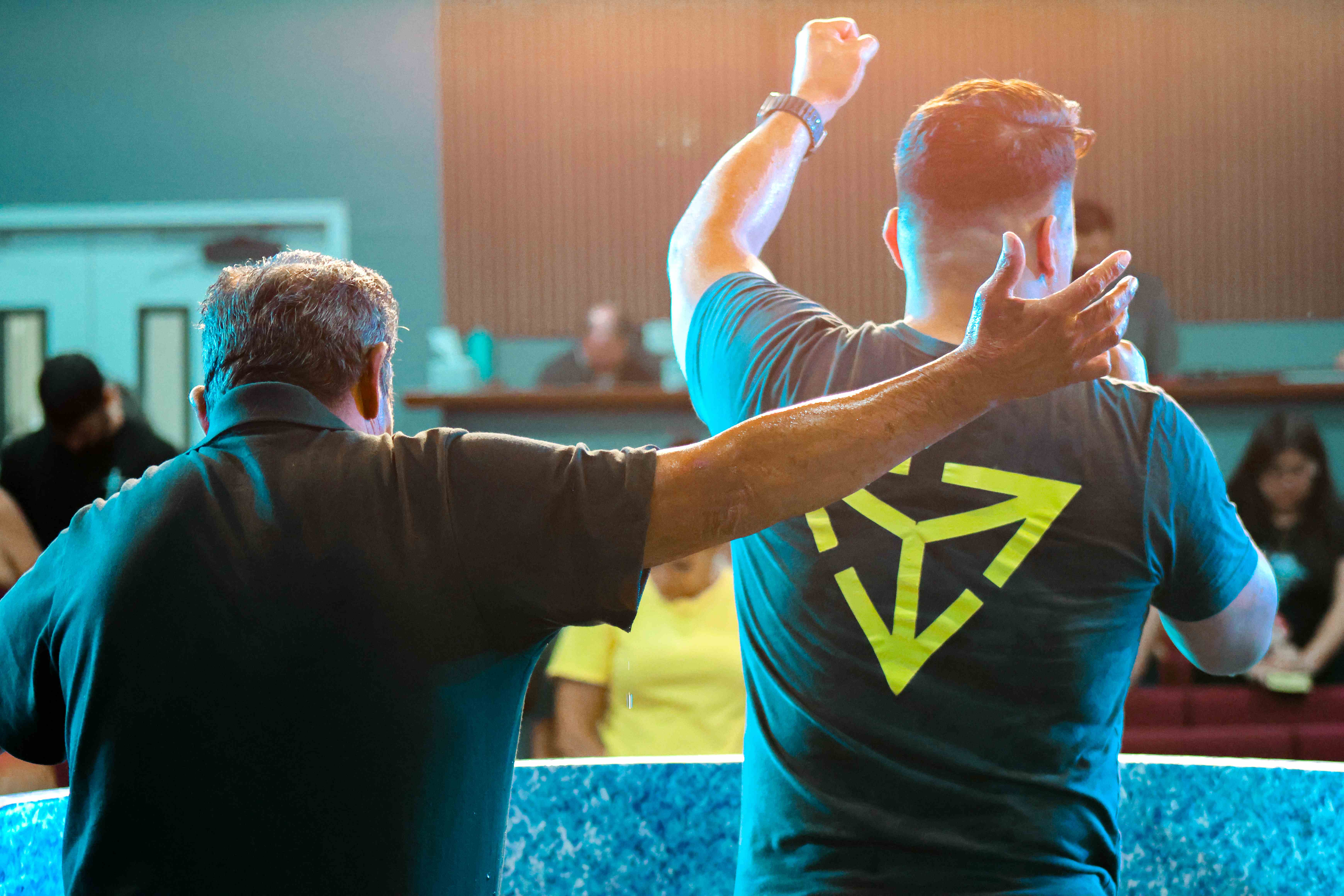 Man raising his fist in celebration beside the baptism pool at Ethos Church