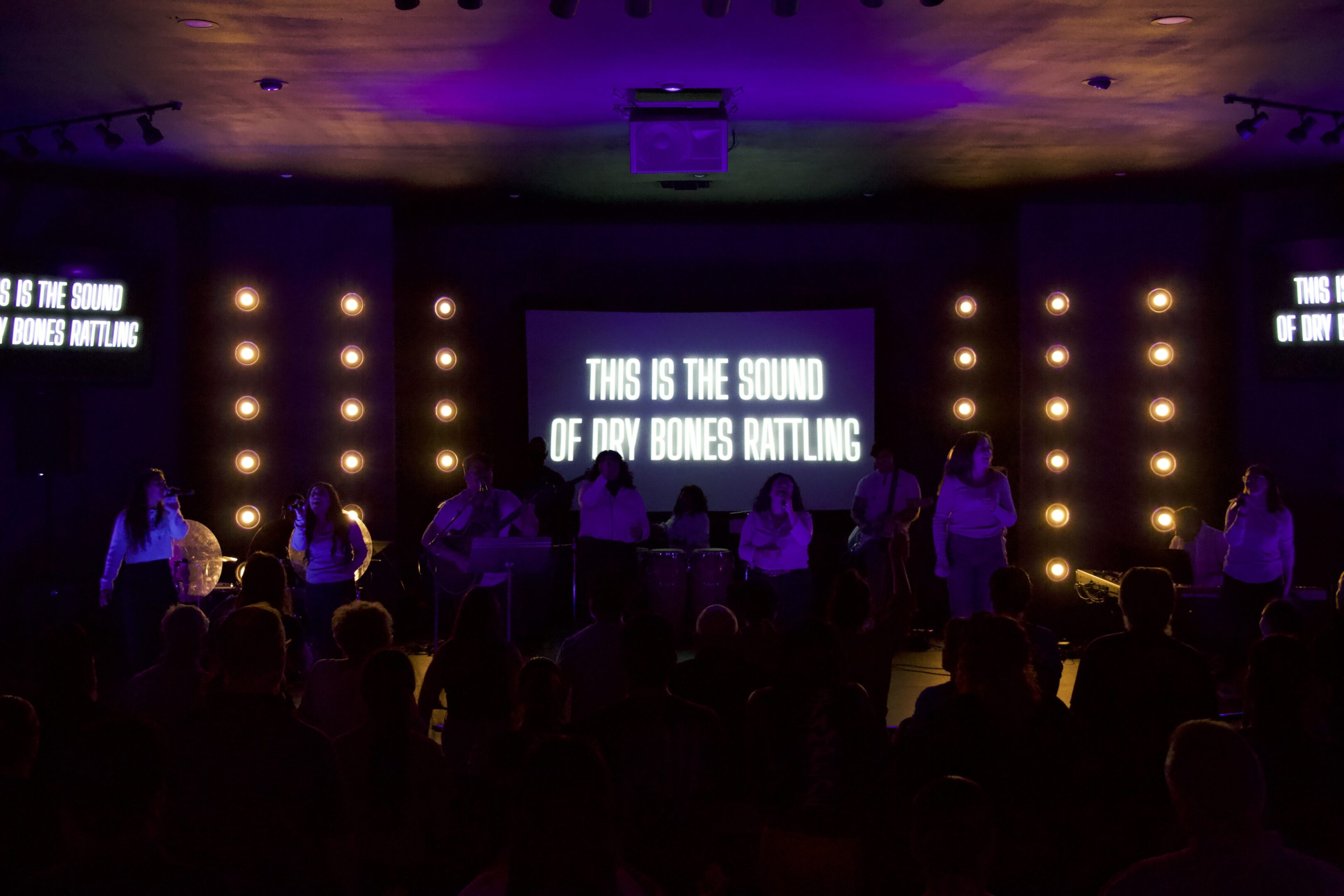 A group of people standing in front of a projector screen.